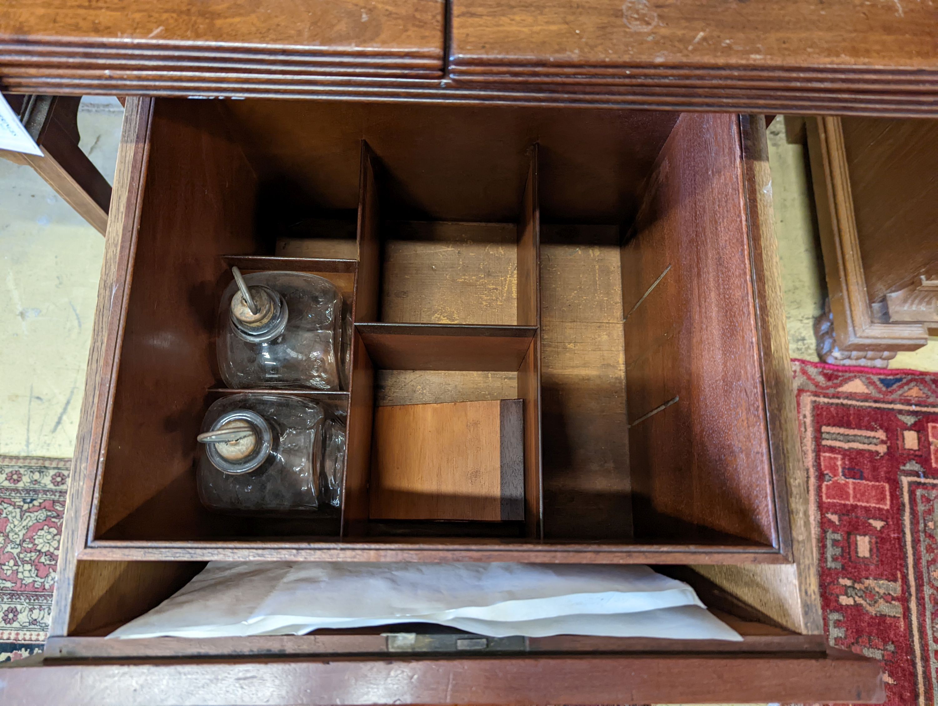 A George III mahogany pedestal designed by C. Wilson, with twin flap top, cellaret drawer now with two decanters and base cupboard, width 53cm, height 87cm